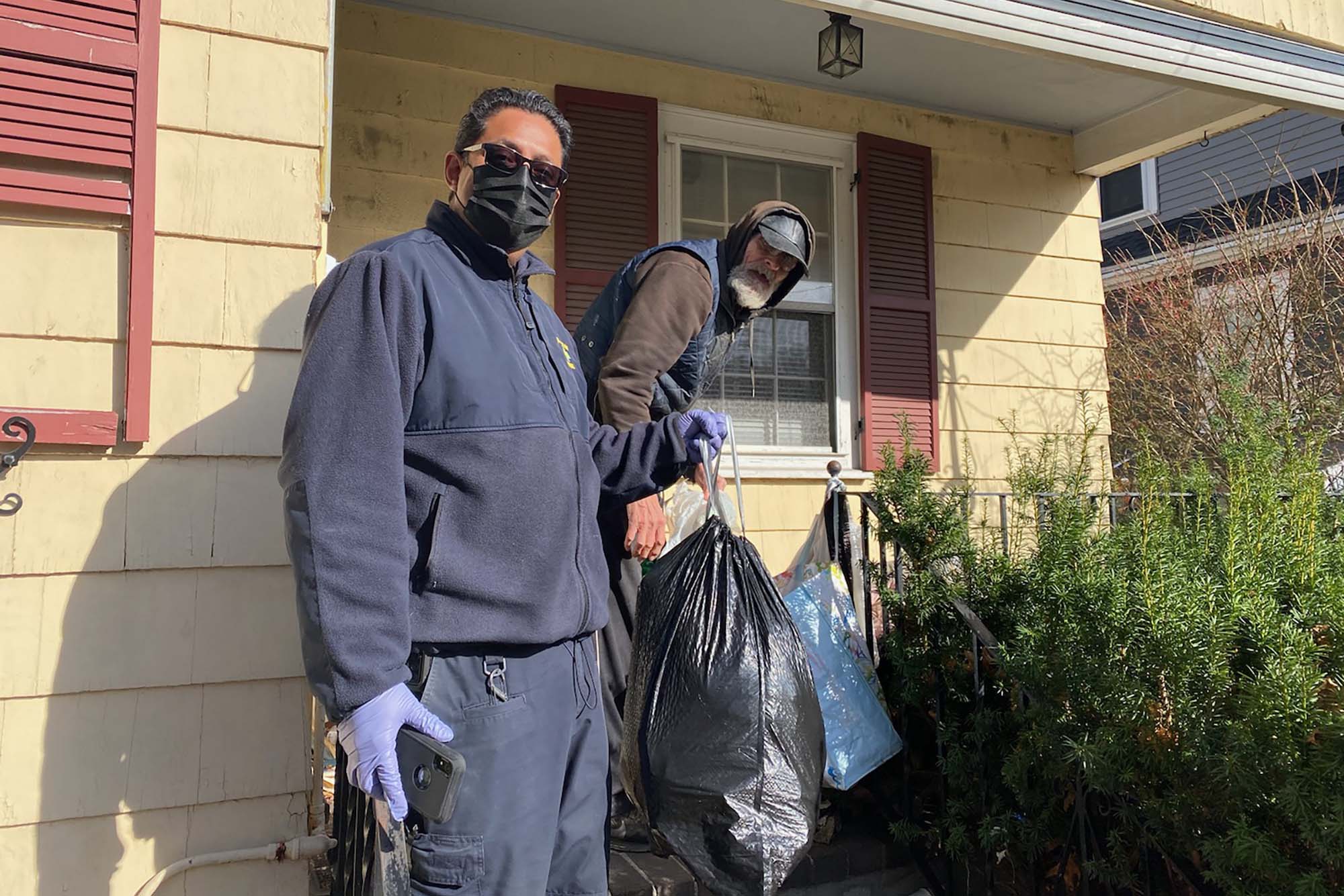 Photo: Abdul Jabbar Muhammad, left, holds a trashbag as he is helping out an elderly individual with maintaining his livelyhood.