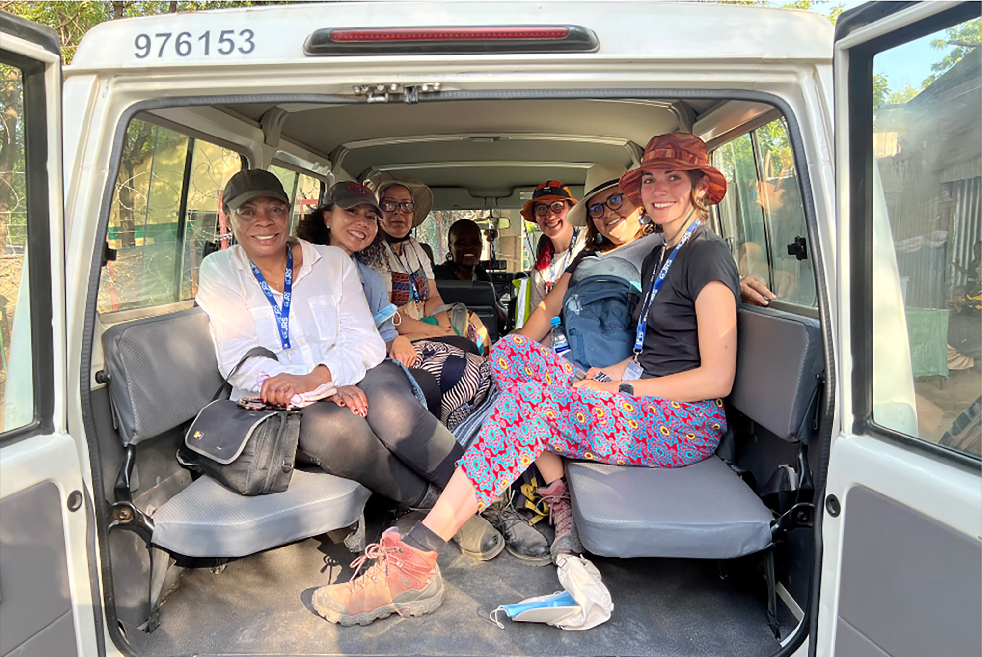 Photo: A group of woman sit in a van all wearing various types of hats and comfortable clothing.
