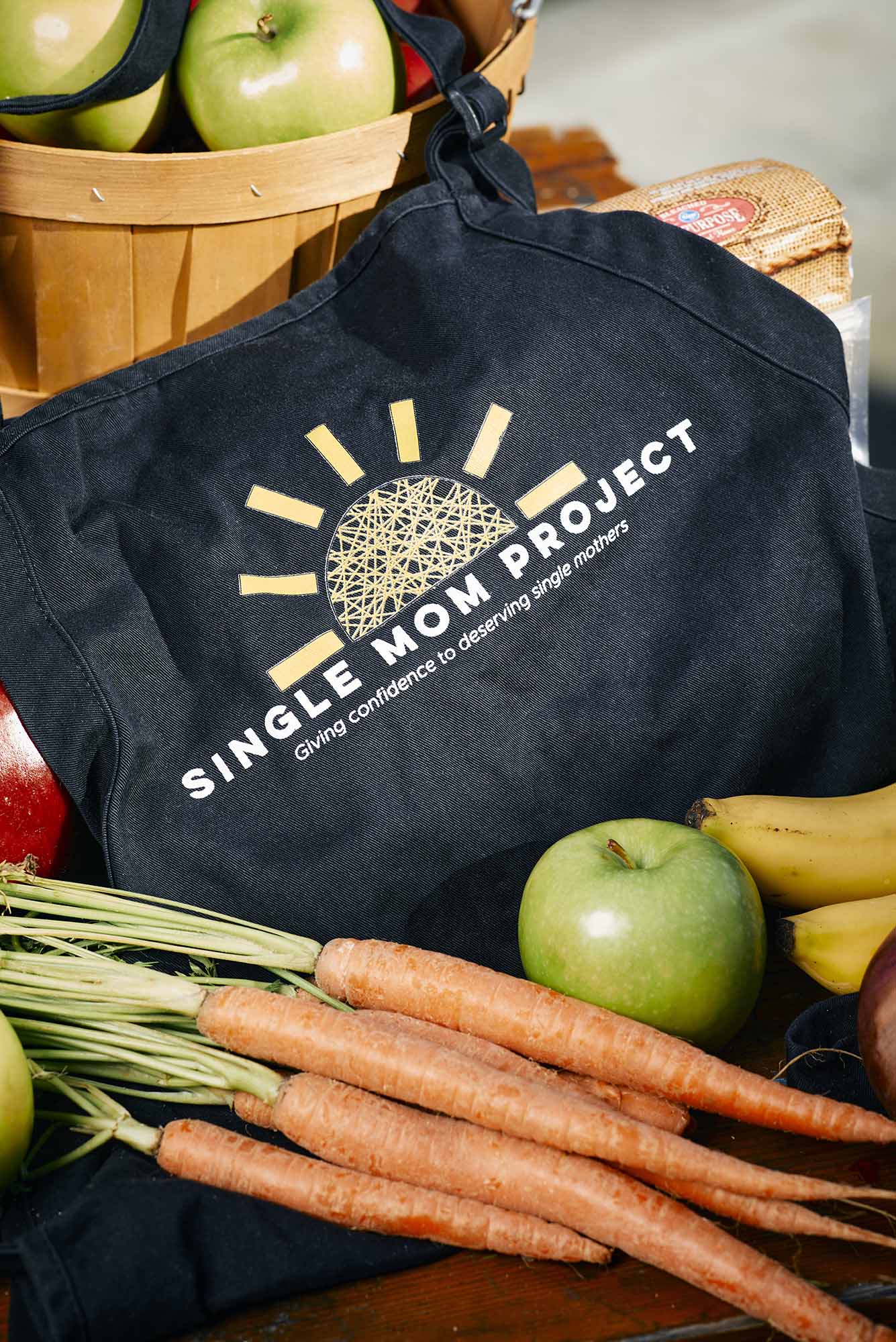 Photo: A photo of a tote bag with the words SINGLE MOM PROJECT printed on top. The tote is surrounded by various amounts of fruit.
