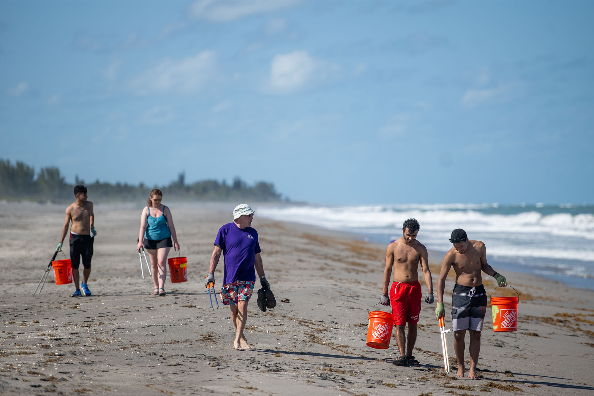 Photo: A group of volunteers pick up trash on a beach in Hobe Sound Florida