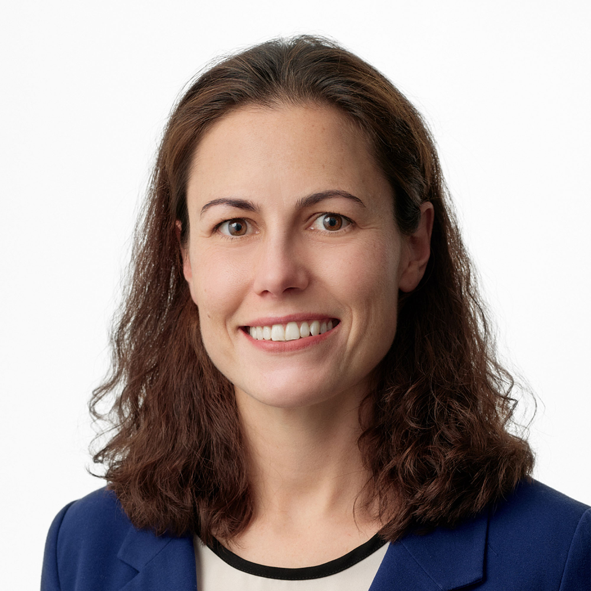 Photo: A woman with dark hair smiling and wearing a blazer in a headshot portrait