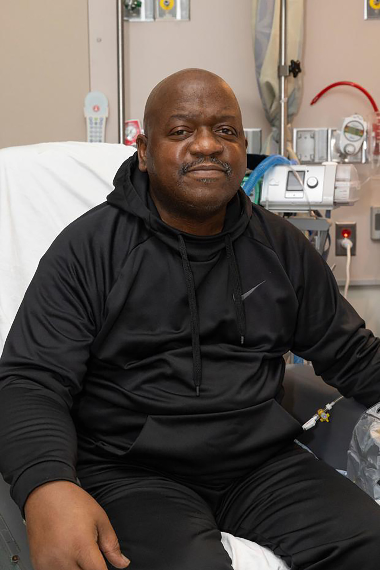 Photo: Rick Slayman, a Black man who was the first to receive a pig organ as a transplant, sits on his hospital bed with a black hoodie.