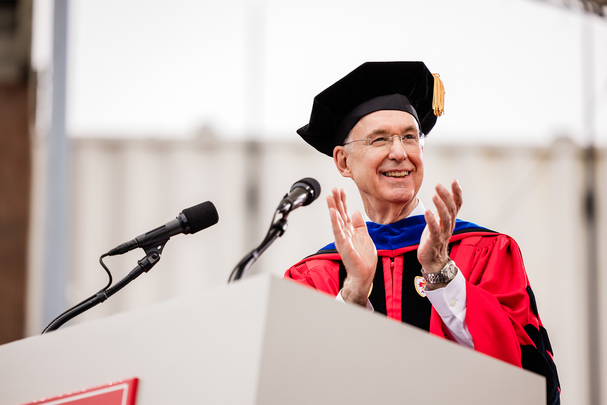 Photo: President ad Interim Ken Freeman claps at the podium at BU's 151st Commencement.