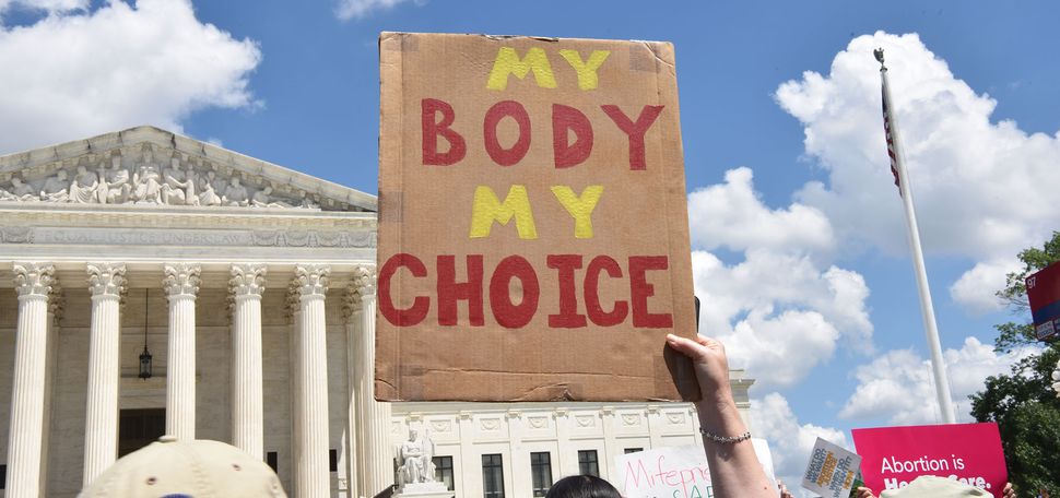 Photo: A picture of a person holding up a sign that says "My Body My Choice" outside of the United States Supreme Court Building