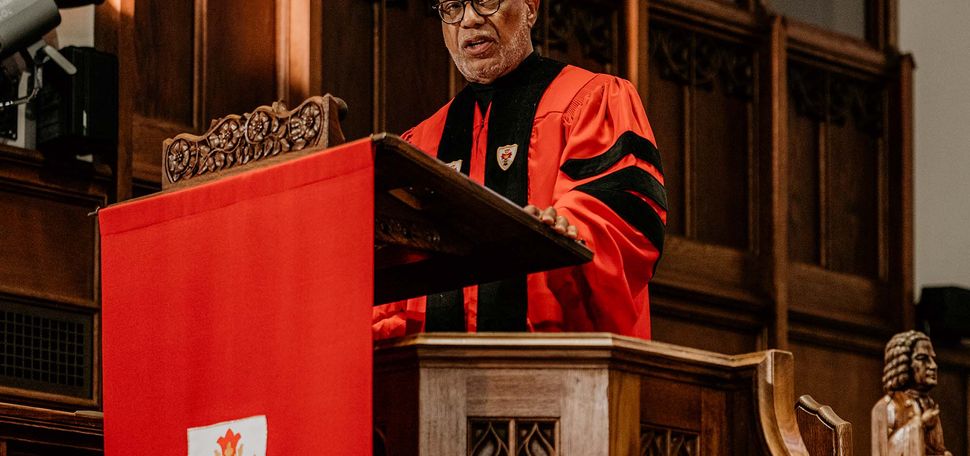 Photo: A man in a red gown gives a speech at a podium draped in a red covering. Baccalaureate speaker Walter E. Fluker (GRS’88, STH’88) told Boston University’s Class of 2024 graduates Sunday to follow the example of BU’s most famous alumnus, Martin Luther King, Jr., in striving for peace and justice. Photo by Kelly Davidson