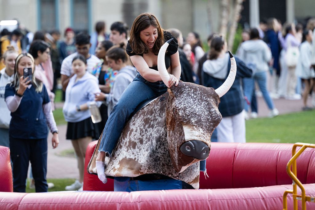 Photo: A picture of a girl riding a mechanical bull at an outdoor event