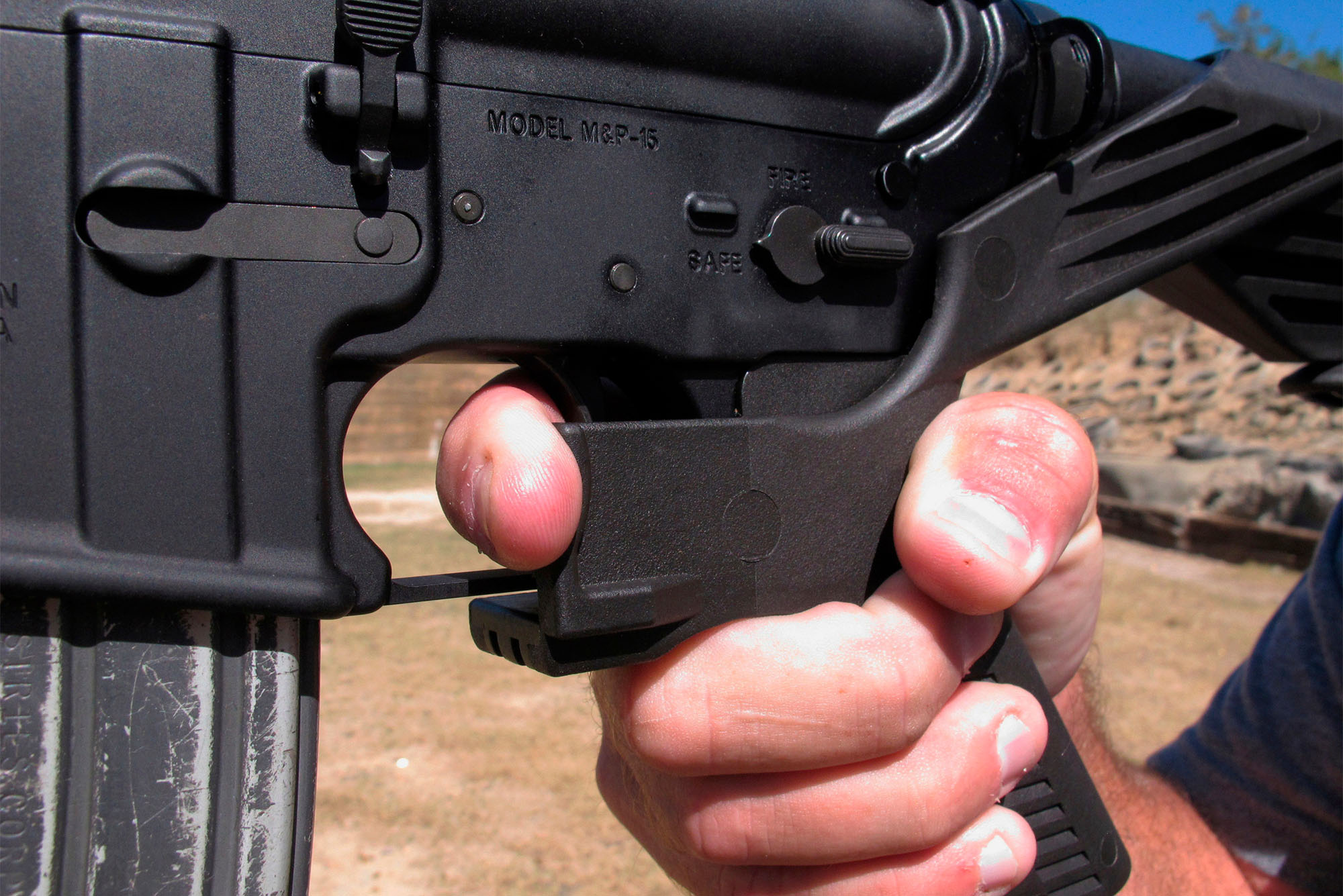 In this Oct. 4, 2017 file photo, a shooting instructor demonstrates the grip on an AR-15 rifle fitted with a "bump stock" at a gun club in North Carolina. What's happened to bump stocks in the year since Las Vegas? There were growing calls the devices in the immediate aftermath of the mass shooting on the Las Vegas strip. Some succeeded, but others did not. (AP Photo/Allen G. Breed, File). A hand is seen grasping a large weapon with a bump stock attached