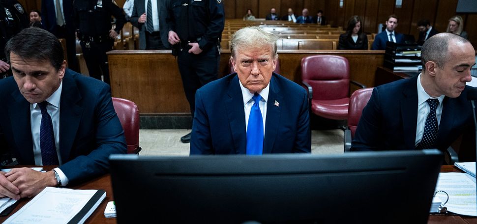 Photo: A man in a blue suit sits in a court room with a dejected look on his face. Former President Donald Trump awaits the start of proceedings during jury selection at Manhattan criminal court, Thursday, April 18, 2024 in New York. (Jabin Botsford/The Washington Post via AP, Pool)