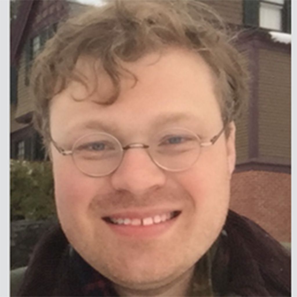 Photo: A picture of a BU professor posing for their headshot. He is wearing glasses and has light curly hair