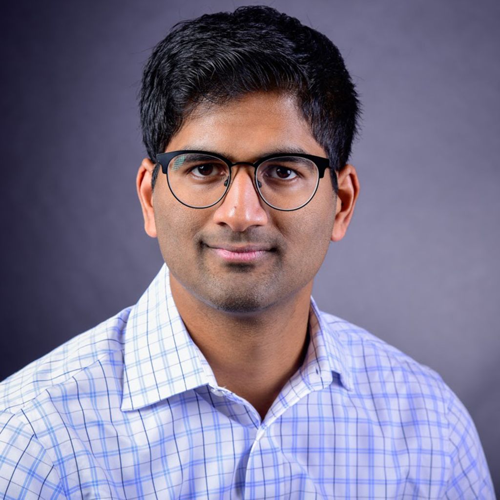 Photo: A picture of a BU professor posing for their headshot. He has short, dark hair and glasses