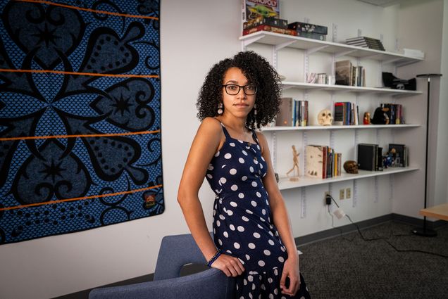 Photo: A picture of Andreana (Andree) Cunningham, a CAS assistant professor of archaeology, standing in front of bookshelves that feature books as well as small skull and human body statues.