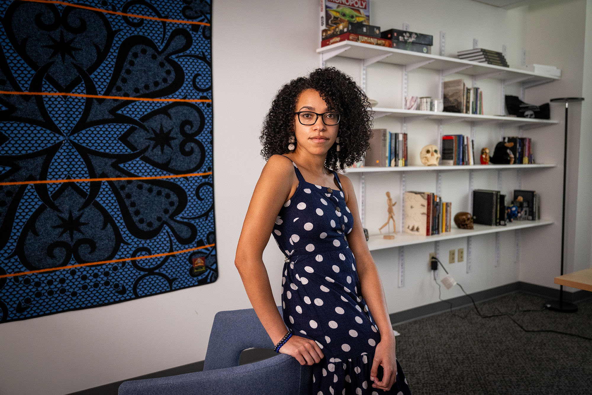 Photo: A picture of Andreana (Andree) Cunningham, a CAS assistant professor of archaeology, standing in front of bookshelves that feature books as well as small skull and human body statues.