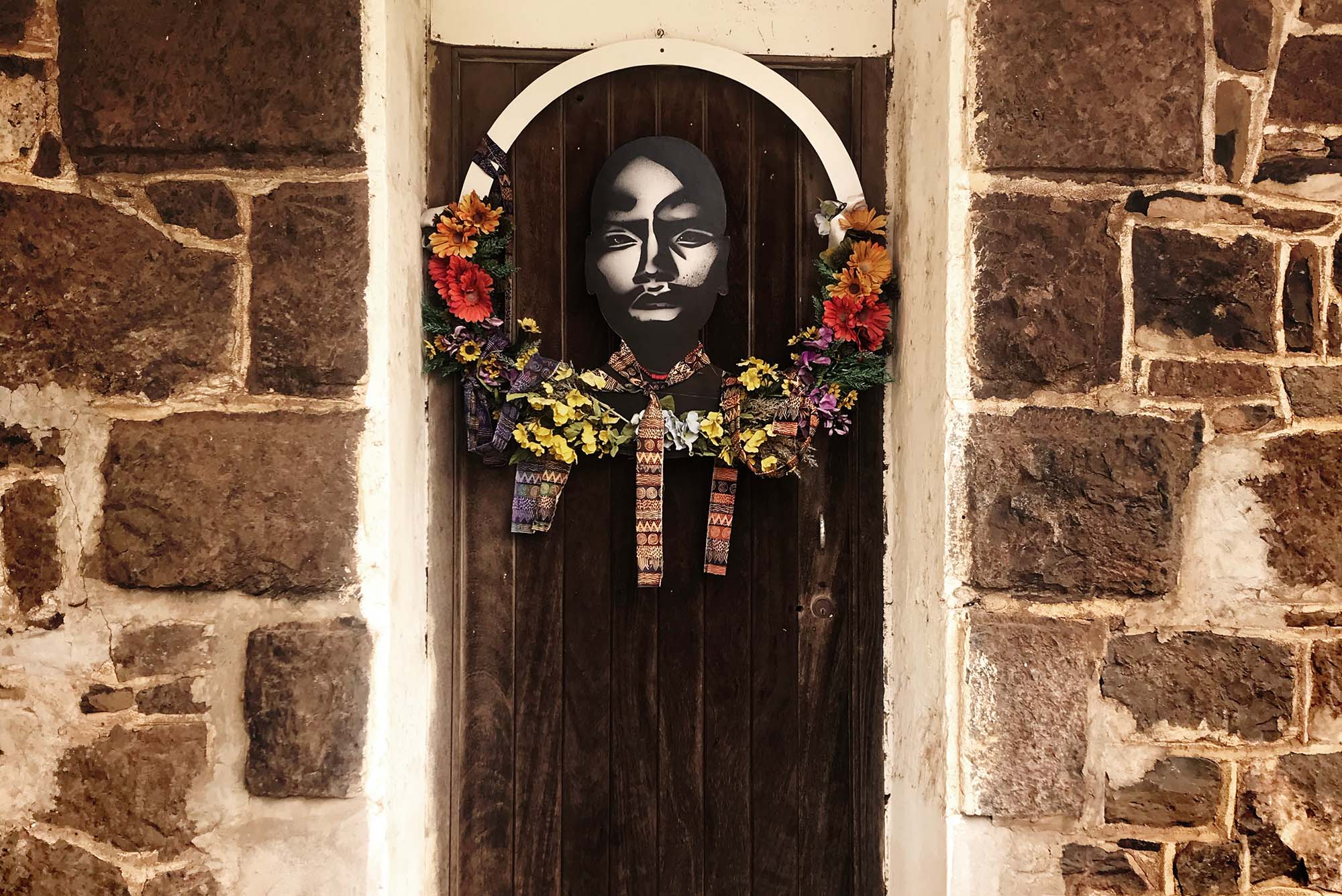 Photo: A picture of a commemorative portrait with a wreath of flowers around it hanging on a door