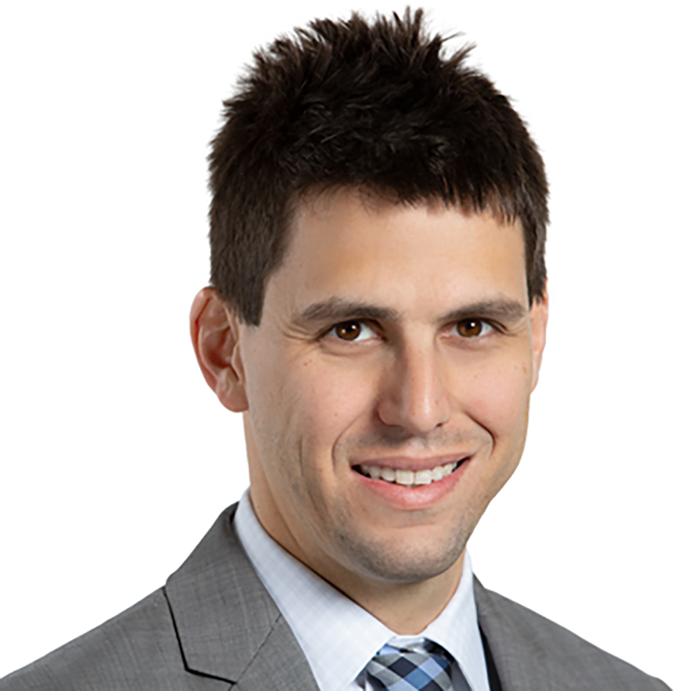 Photo: A portrait shot of Cody Jacobs, a white man with short brown hair, gray suit, smiles for the camera.