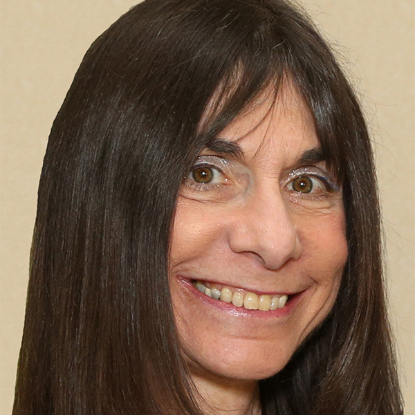 Photo: Portrait of a woman with sparkly eye makeup and long dark hair posing for a headshot