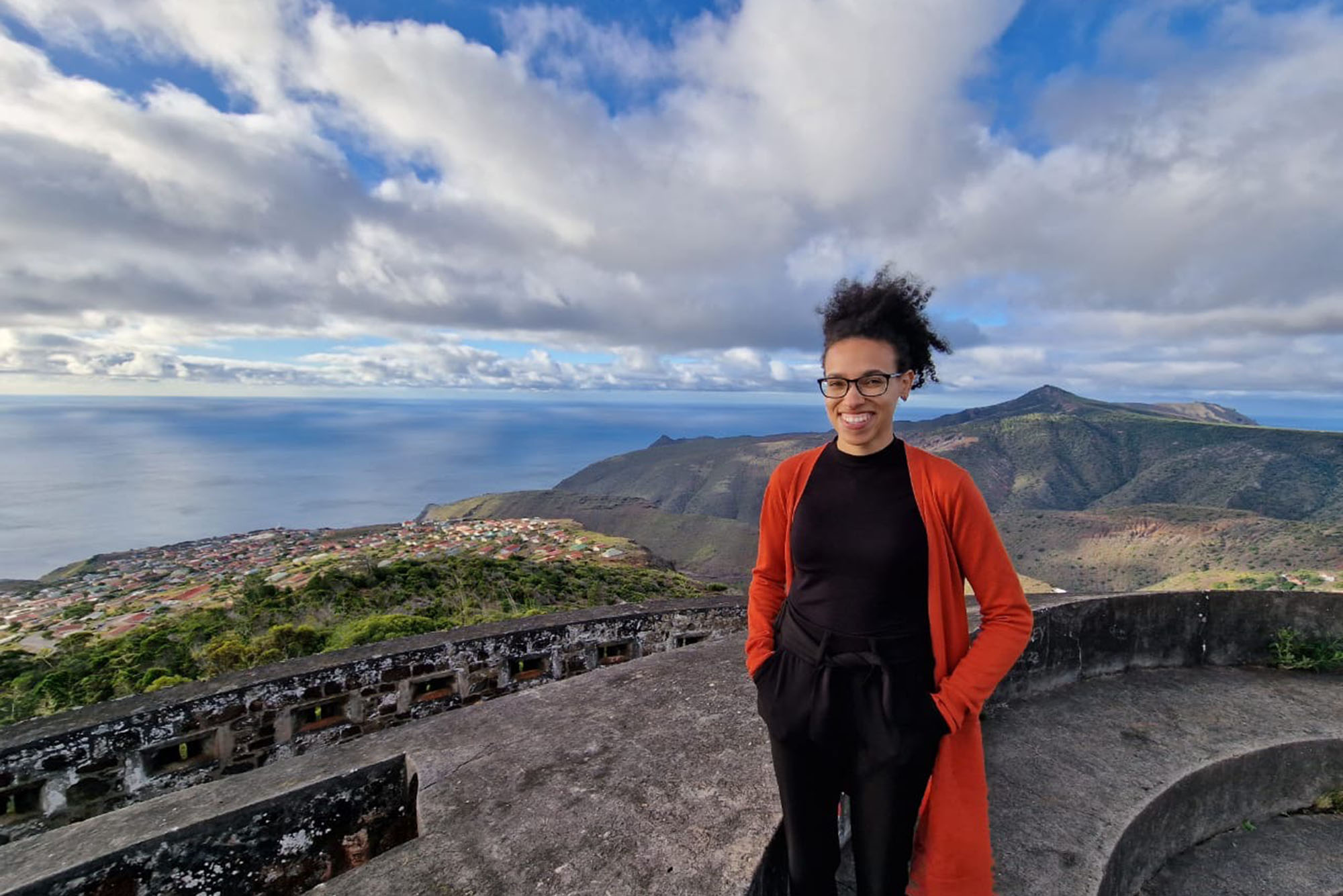 Photo: A picture of Andreana Cunningham standing in front of the landscape of Saint Helena's