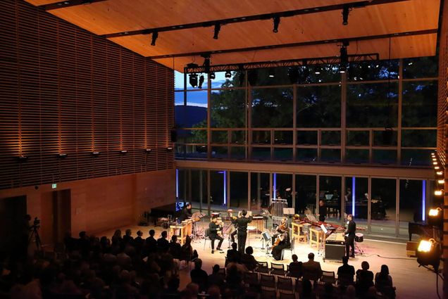 Photo: A wide shot of a concert stage as an orchestra performs in the center.