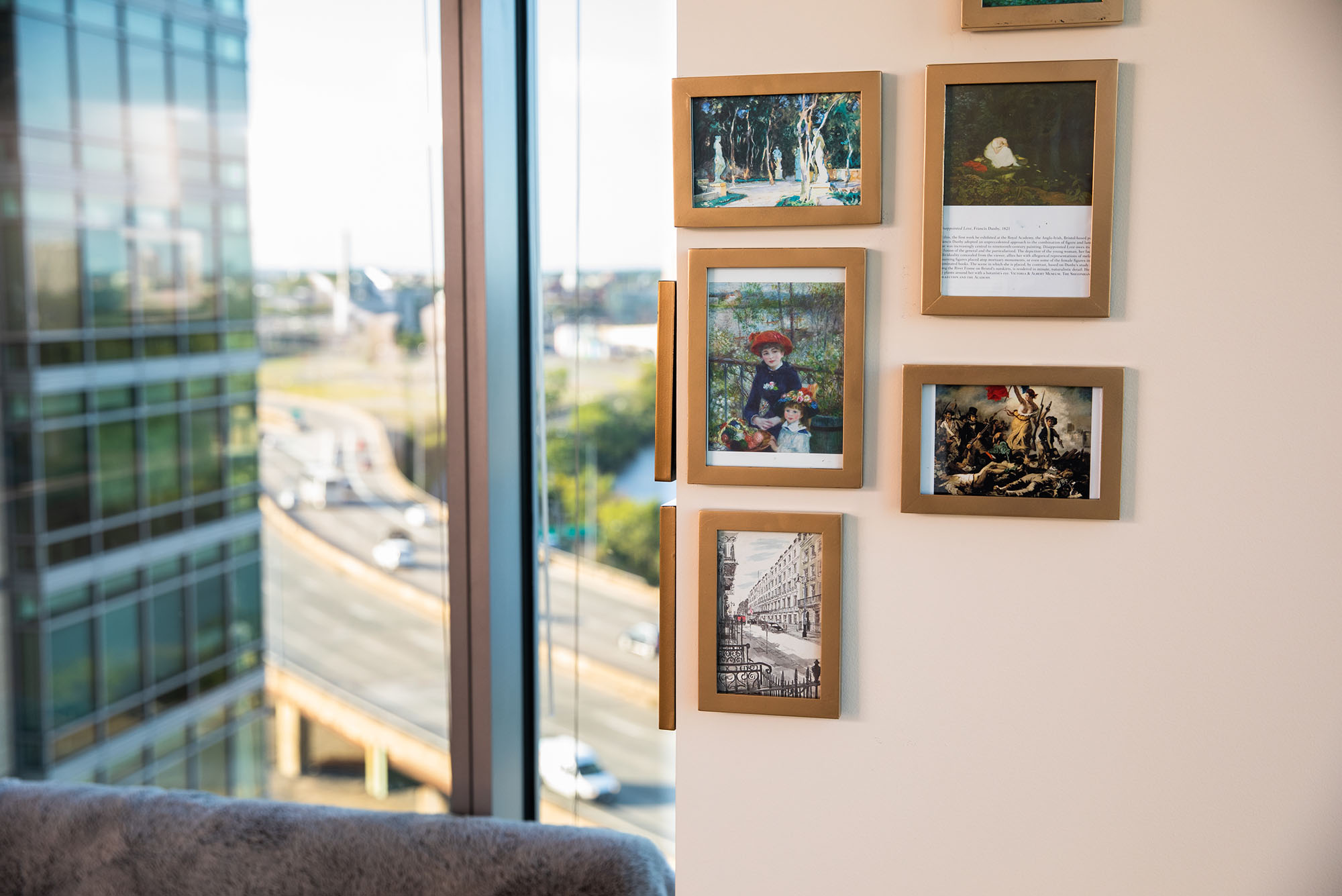 Photo: A picture of a dorm wall next to a window with a small gallery wall of art pieces within wooden frames