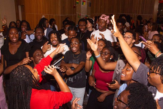 Photo: Many students gathered around a woman with a mic, all singing karaoke at the Howard Thurman Center