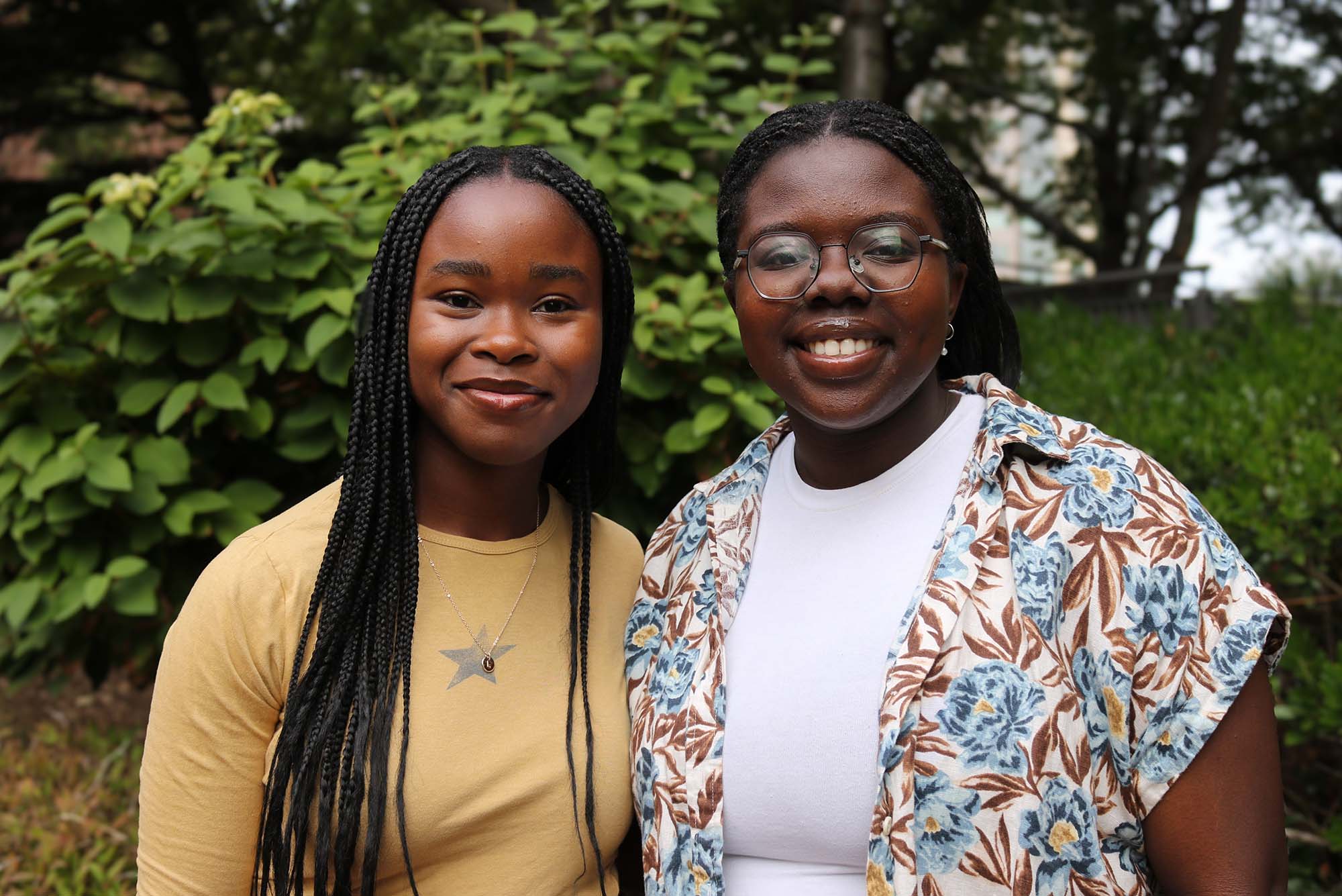 Photo: Two students smiling and posing for the camera while in a park