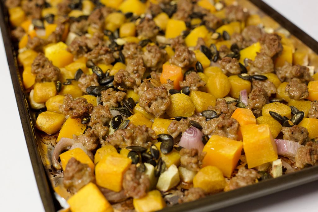 Photo: A close-up of various squash, meat, onions, and shallots on a sheet pan.