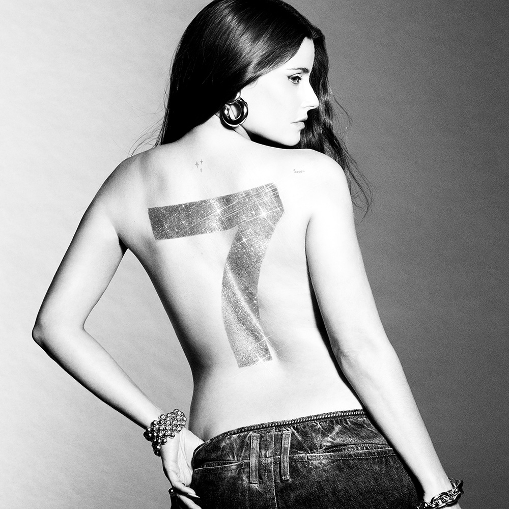 Photo: Album cover for "7" by Nelly Furtado. It features the artist topless and turned so the camera only sees her back, which has a "7" painted across it