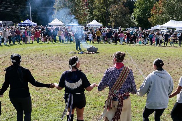 Photo: People participating in an Indigenous Peoples Day Ceremonial Celebration as they hold hands in a circle.