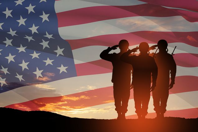Photo: Three USA army soldiers saluting in front of a background of an American flag