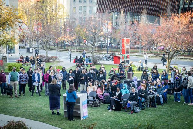 Photo: A crowd of people gather for BU's Trans Day of Remembrance on a green lawn.