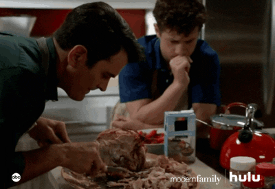 A clip from Modern Family's Thanksgiving episode, with the dad carving the turkey while the son has his chin leaning on his hand with his eyebrows furrowed.