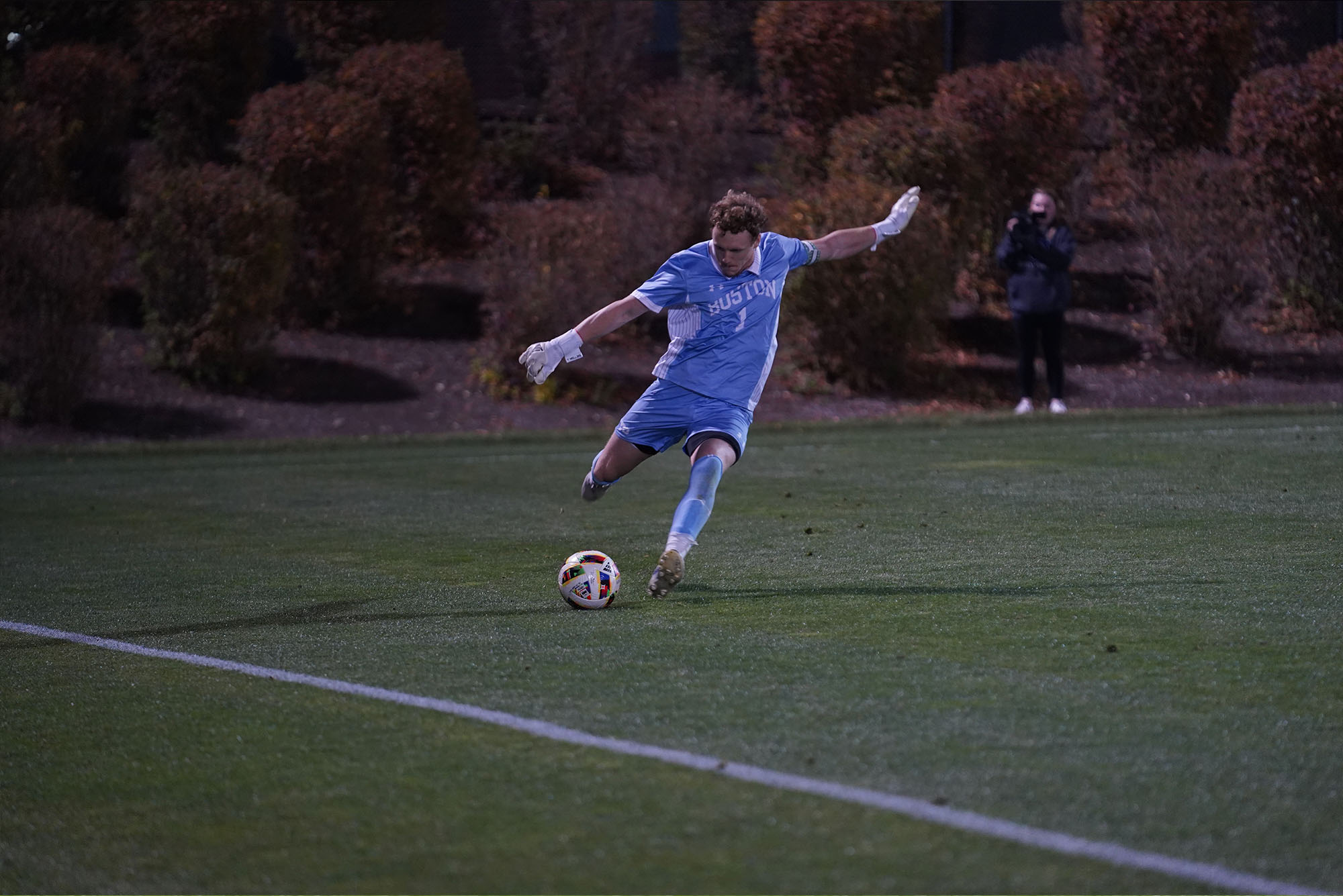 Photo: A picture of a male soccer player in a blue uniform that says "Boston" kicking a soccer ball on a field