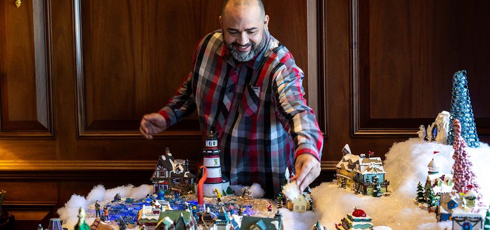 Photo: A man assembling a ceramic winter village