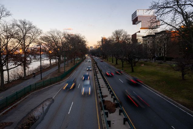 Photo: A highway during sunset with cars out of focus. Along the highway is the Charles River and Boston University Duan Family Center for Computing & Data Sciences Building