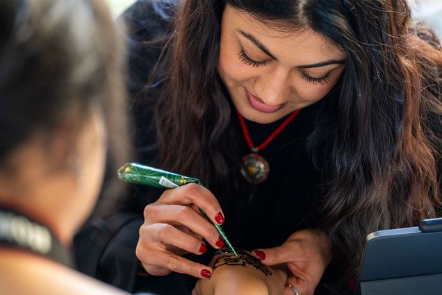 Photo: 12/6/24 -- Boston, MA, USA Amira Sheikh (CFA’25) creates a henna tattoo for Interim managing director of BU Arts Initiative Elana Harris (MET’23) during the BU Art Market dec 6 in the GSU Link. The market made a variety of creative items available for passers-by to purchase including jewelry, artworks, baked goods, knitted and crocheted pieces. Photo by Cydney Scott for Boston University Photography