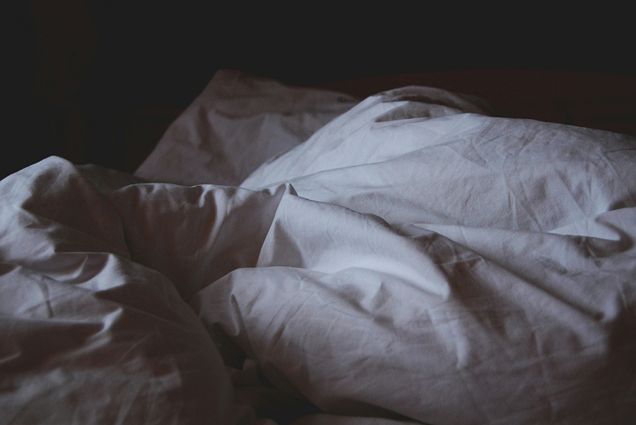 Photo: A bed with white, rumpled blankets and pillow covers