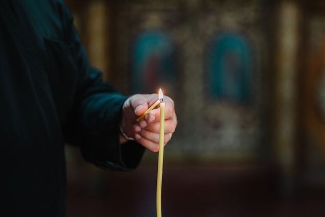 Photo: A stock photo of a clergy member lighting a candle in a church.