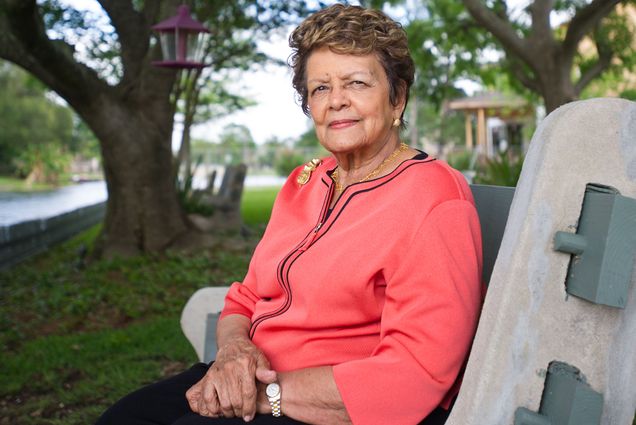 Photo: A picture of BU alum and civil rights advocate Sybil Haydel Morial wearing a long-sleeve peach top and sitting on a bench in a park