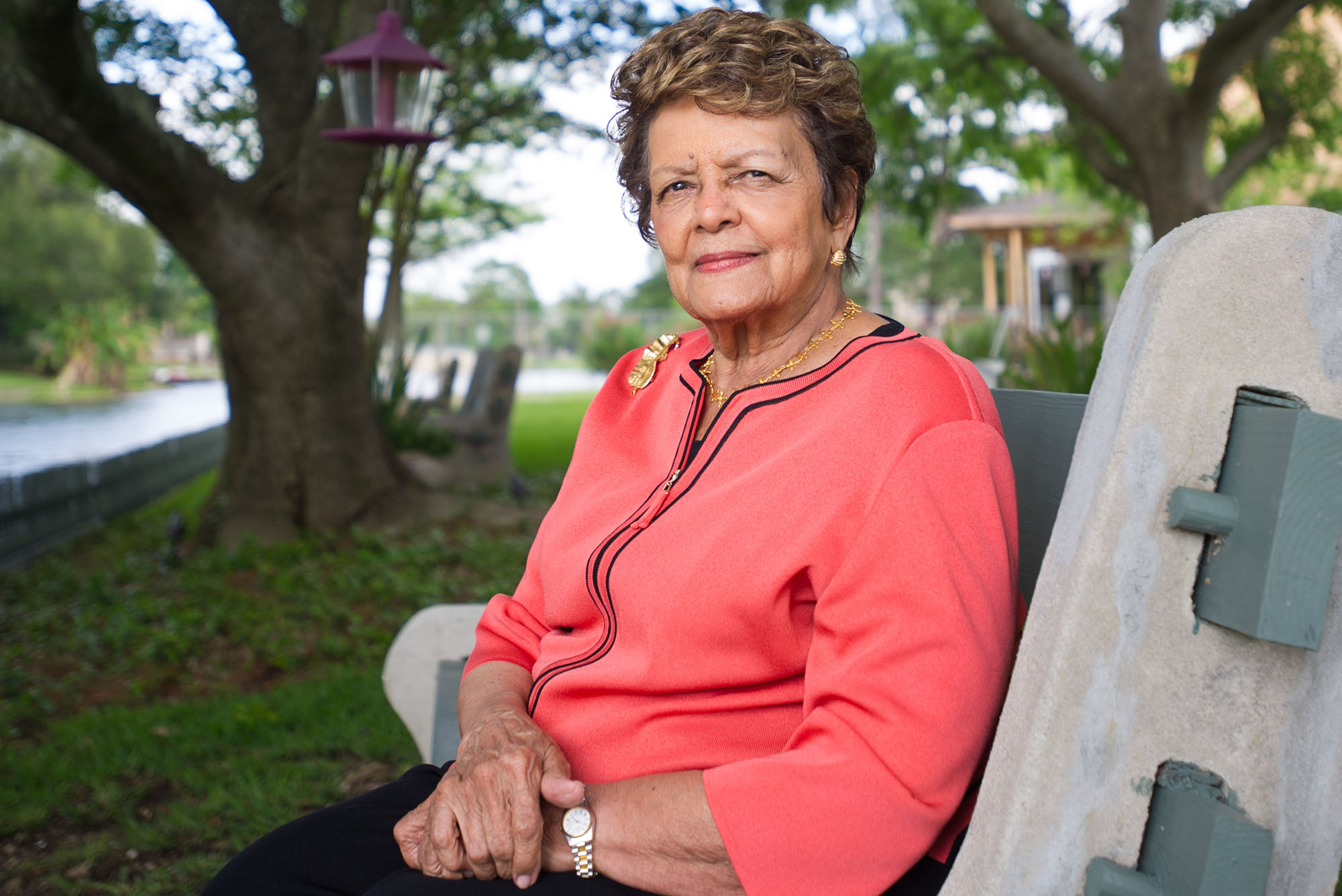 Photo: A picture of BU alum and civil rights advocate Sybil Haydel Morial wearing a long-sleeve peach top and sitting on a bench in a park