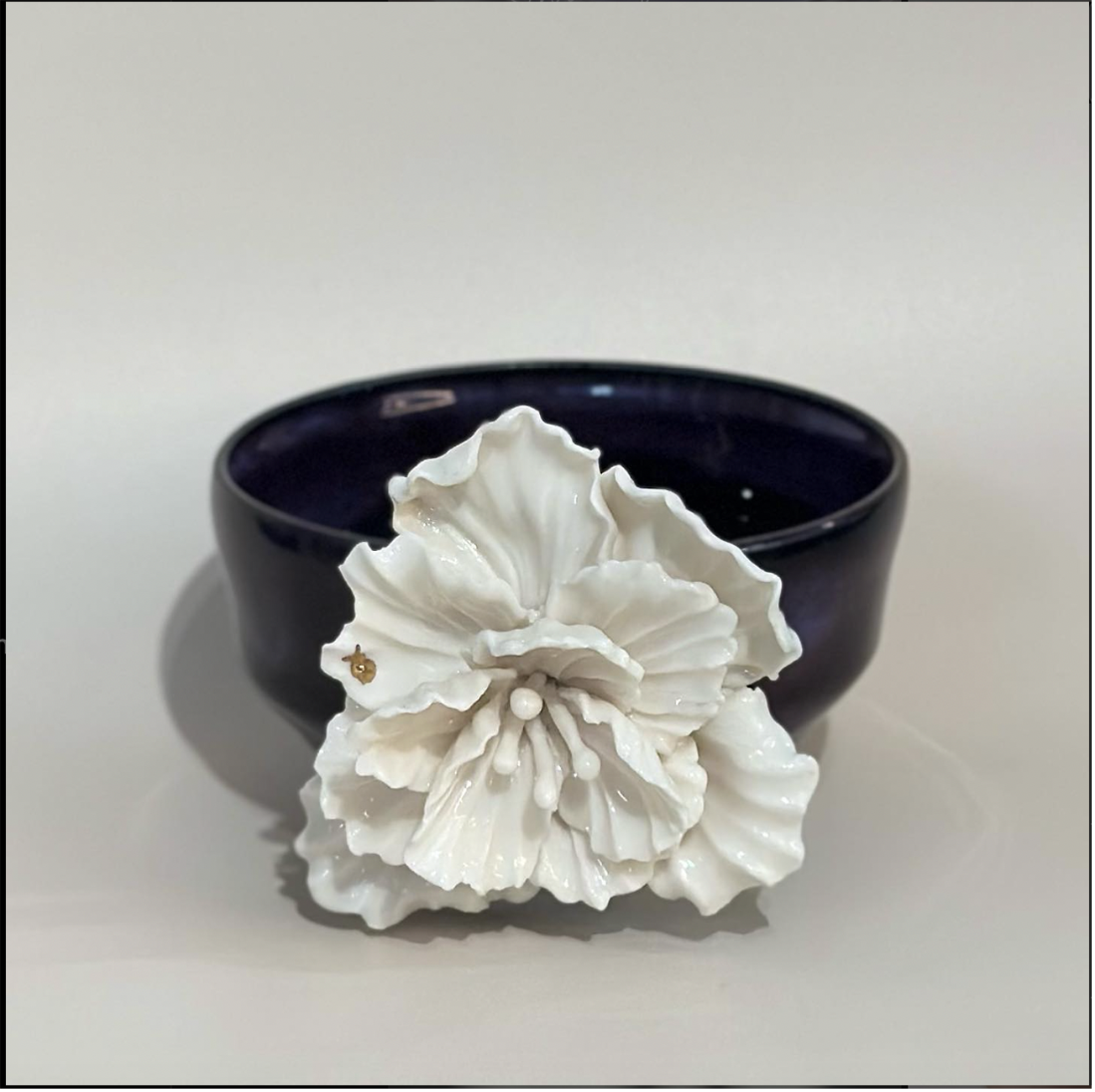 Photo: A black ceramic bowl with a white flower.