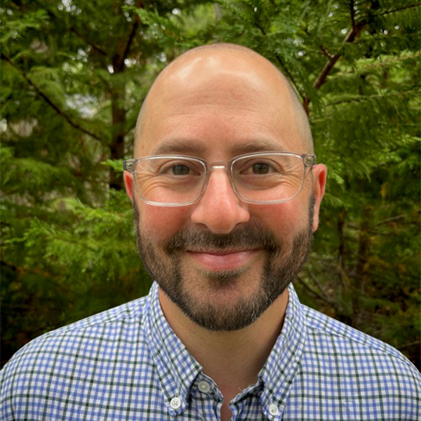 Photo: A bald white man with a beard and soft smile wearing a collared shirt