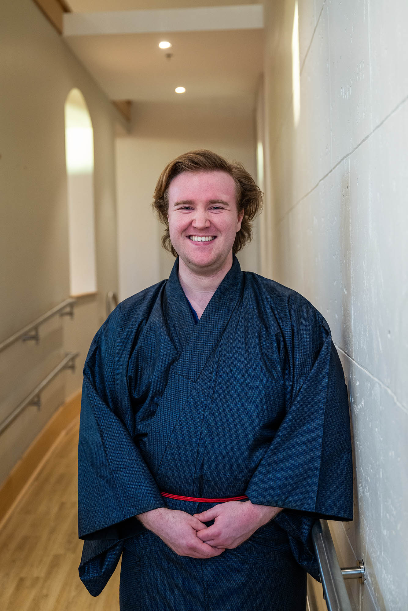 Photo: CFA senior Chris Ellars, a young white man wearing a traditional navy kimono, smiles for a photo.
