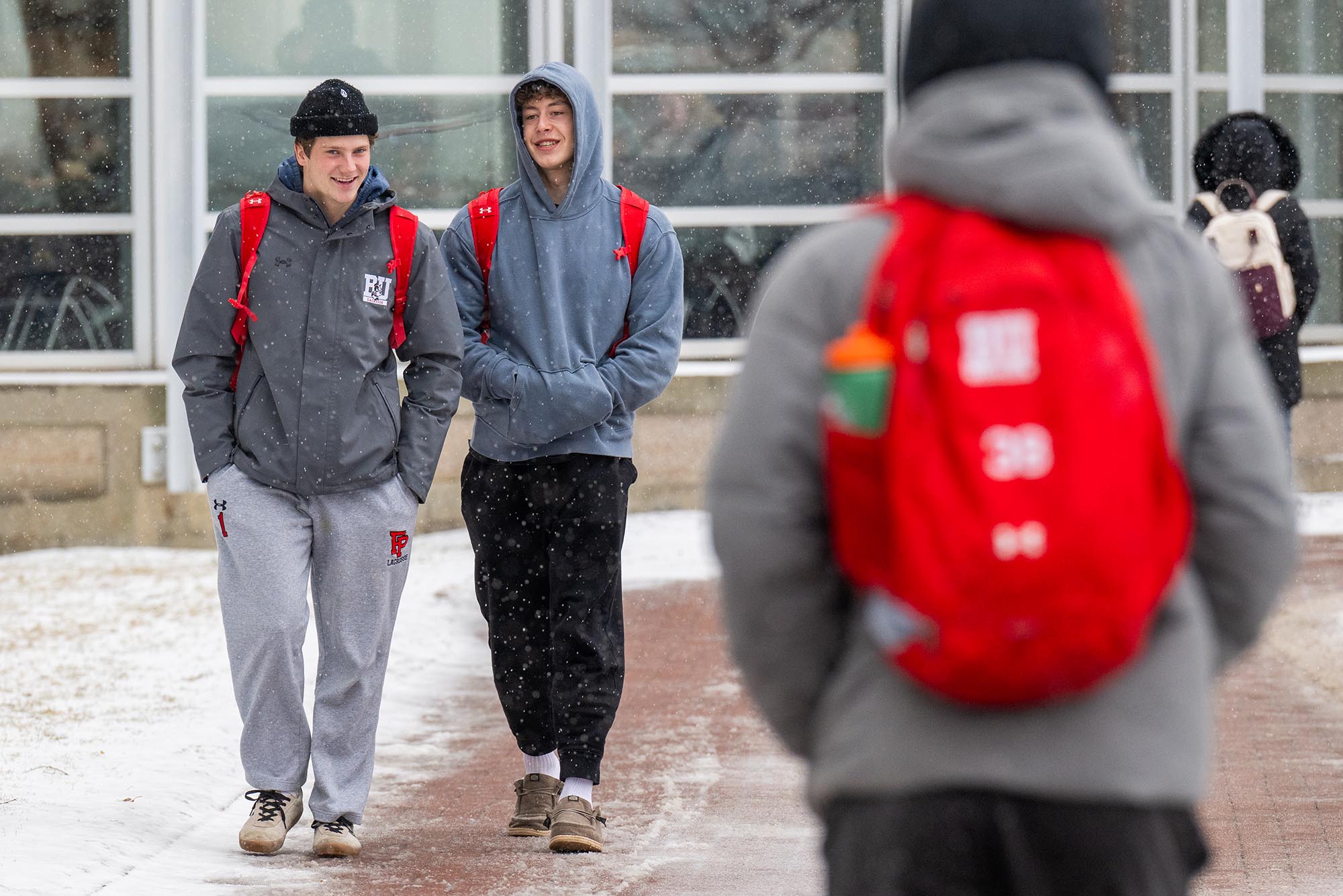 Photo: A couple of BU students stroll in the snow, kept warm by their all-gray sweatsuit.