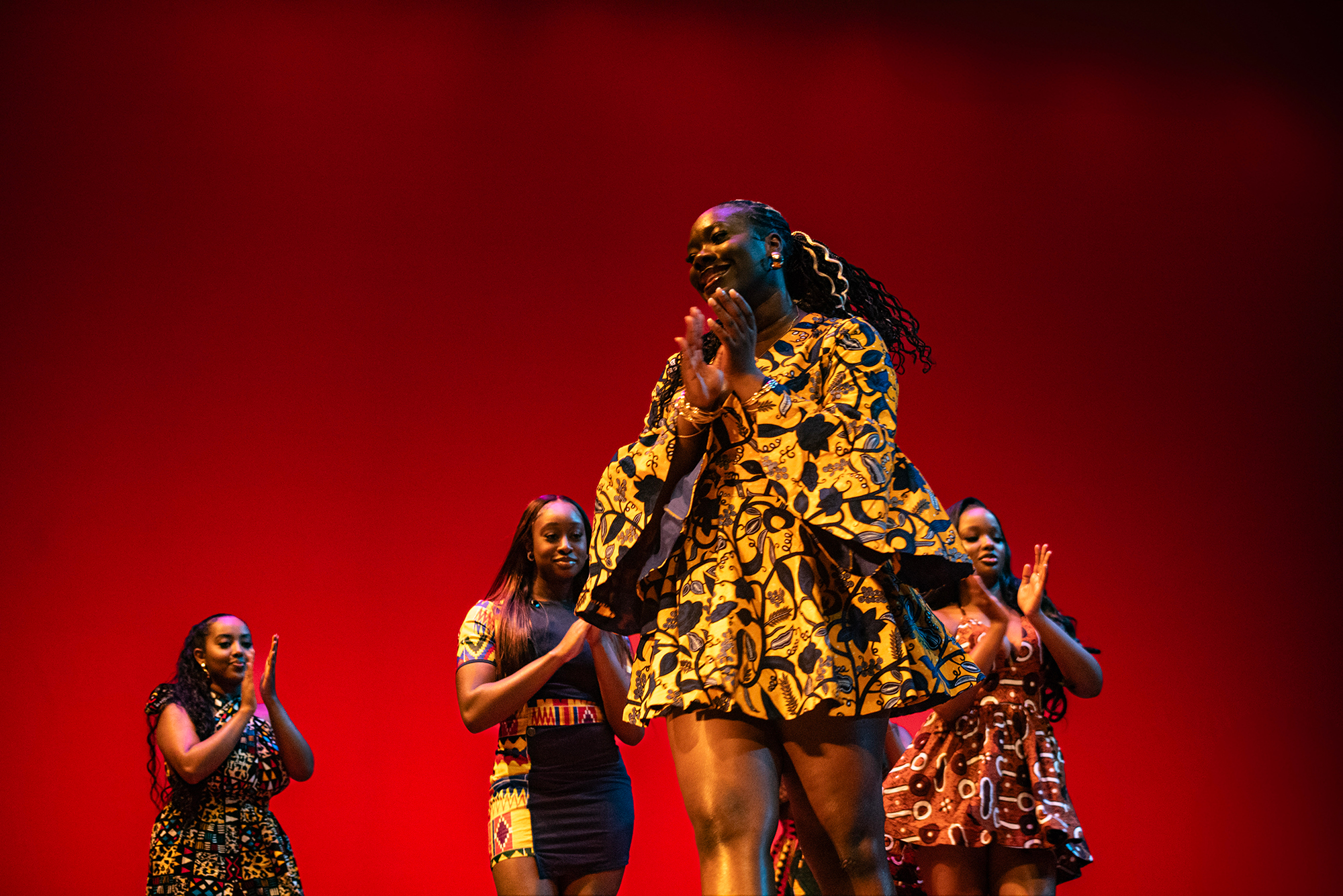 Photo: Four Black female students walk in a fashion show with a red backdrop behind them
