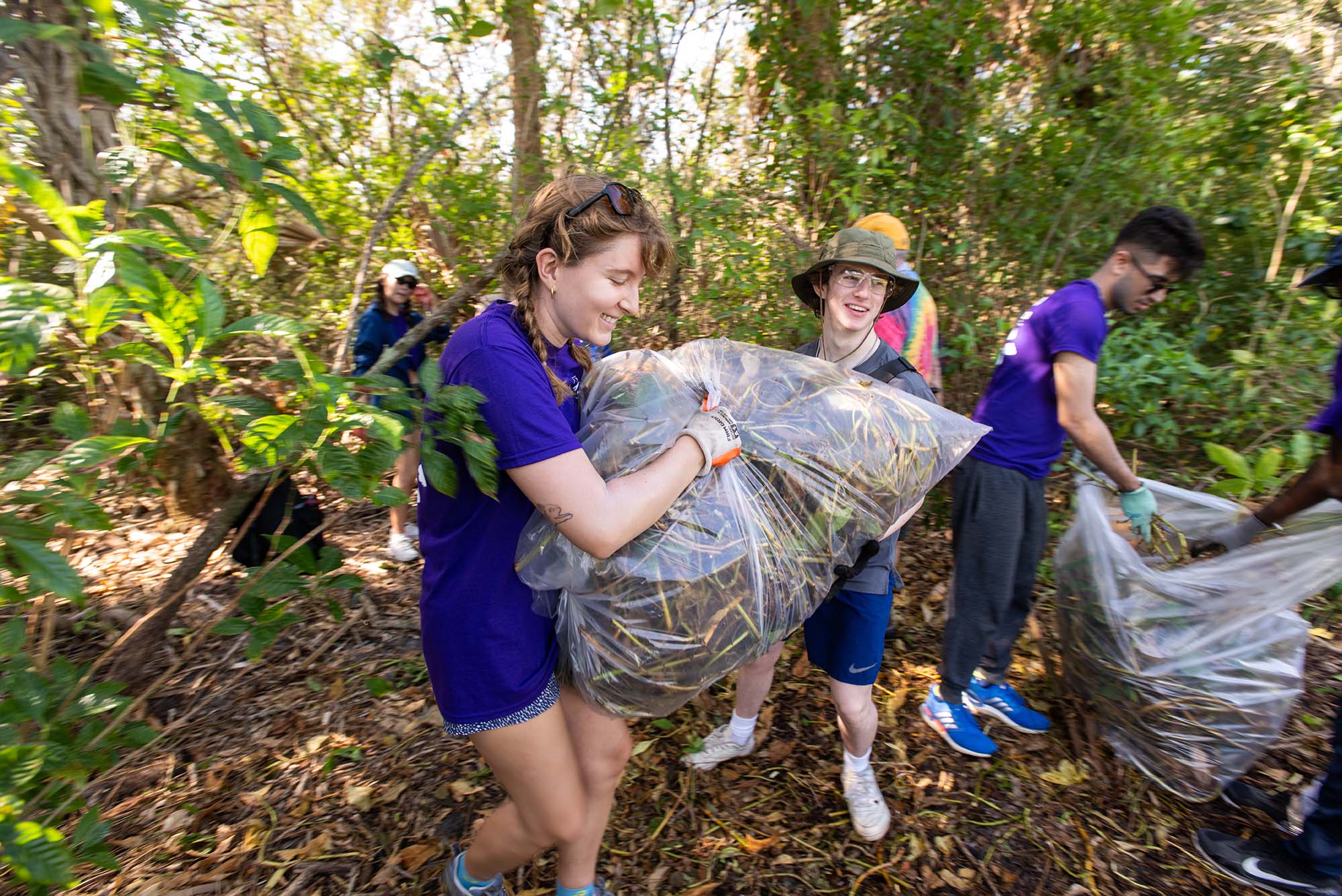 Photo: Students carrying bags of weeds as they dispose of them during an Alternative Service Break trip