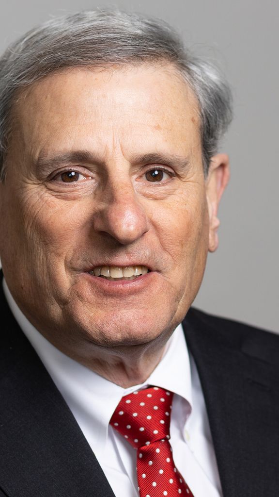 Photo: A man smiling for a portrait while wearing a dark suit and vibrant red tie