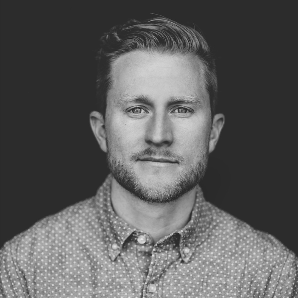 Photo: Portrait of a young man with short hair wearing a button up shirt.