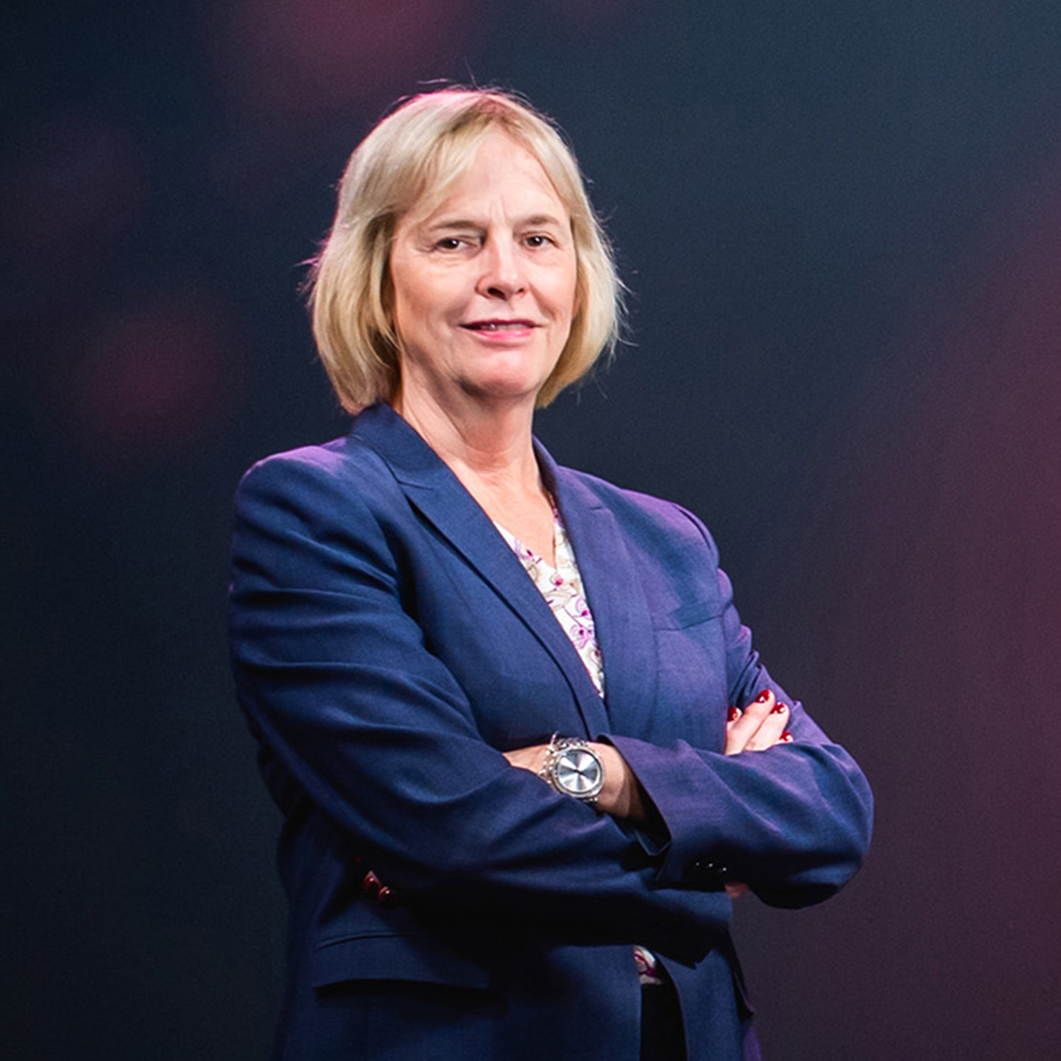 Photo: A woman standing on a stage with her arms crossed in front of her