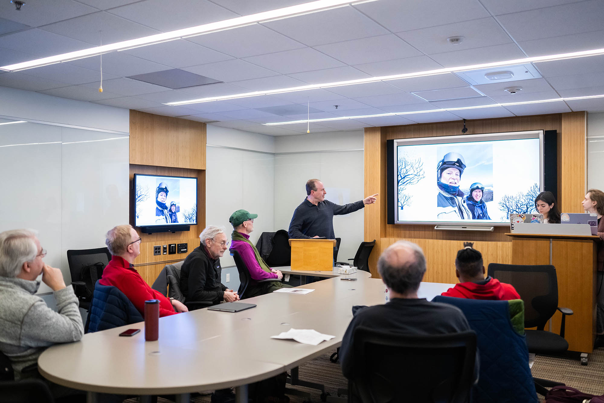 Photo: A group of people meeting in a board room with a presentation on the projection.