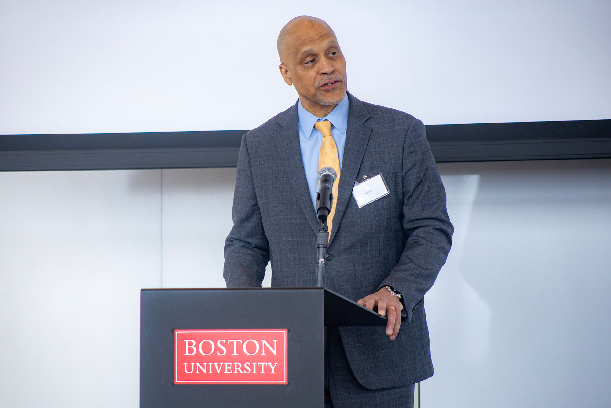 Photo: A man standing behind a podium and speaking in front of a crowd