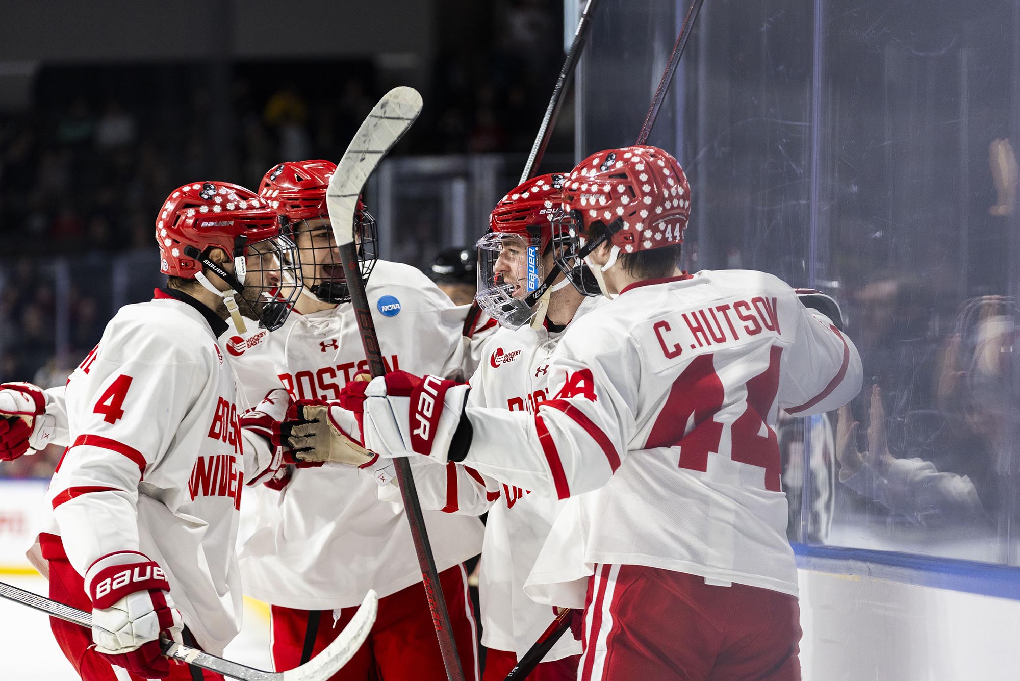 Photo: A group of BU men's hockey huddle and talk on the ice in their uniform.
